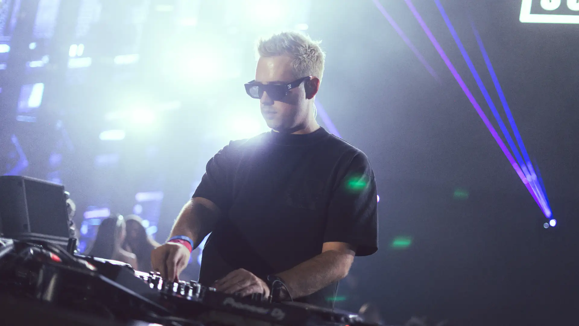Scott Forshaw raising arms behind decks at Terra Solis Dubai with red stage lighting