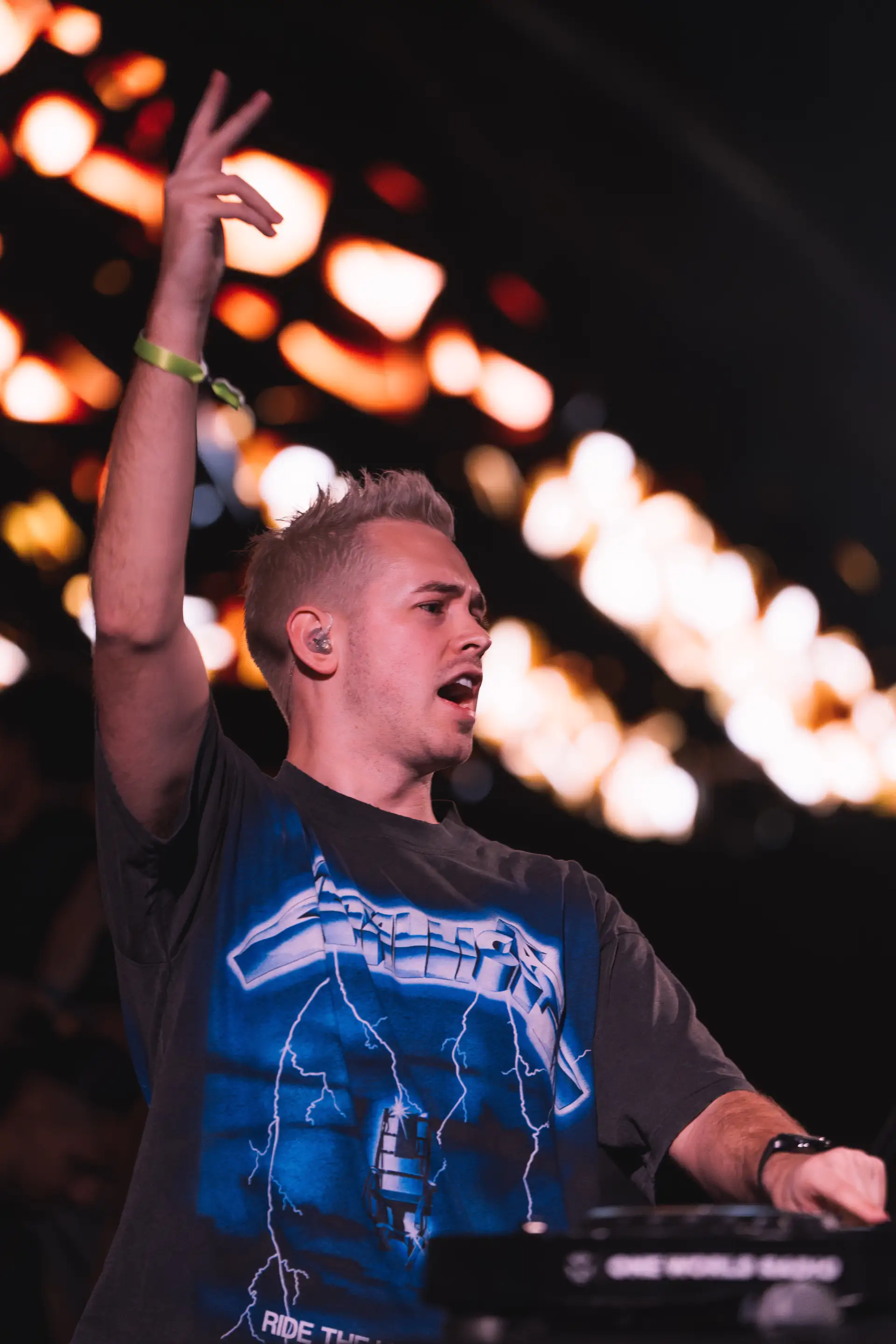 Scott Forshaw on stage in a Metallica tee with arm raised to a festival crowd